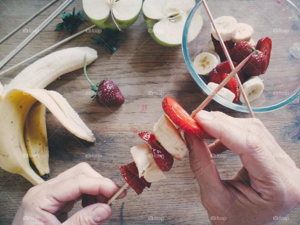 Person hand putting fruits in cocktail stick