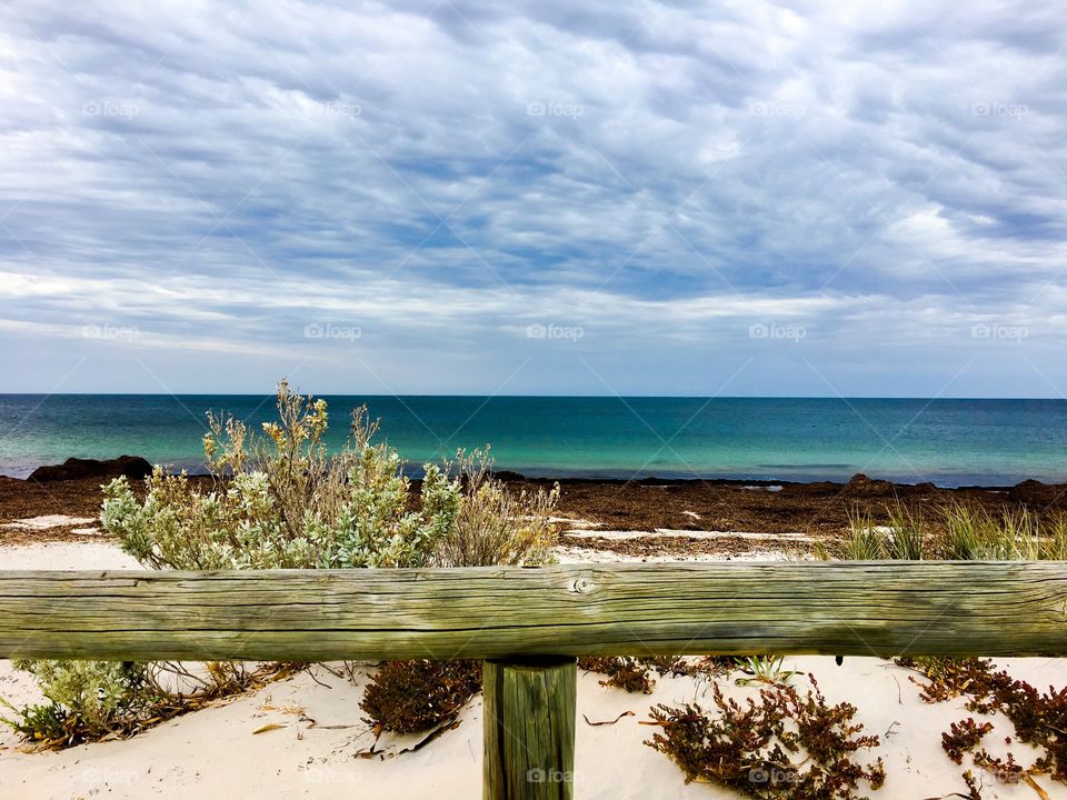 Remote tropical beach near turquoise ocean with weathered wood railing foreground suitable as background image or wallpaper 