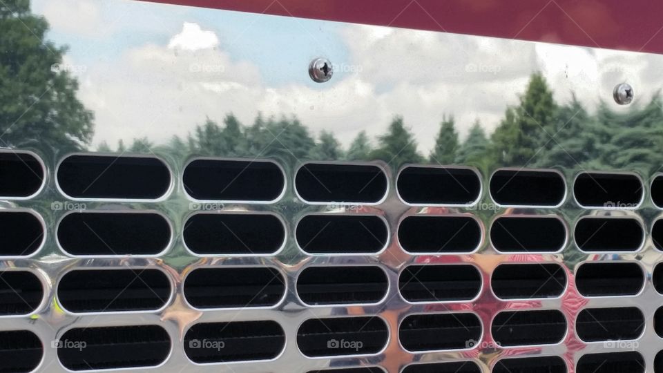 Reflection of the skyline on a fire truck grate