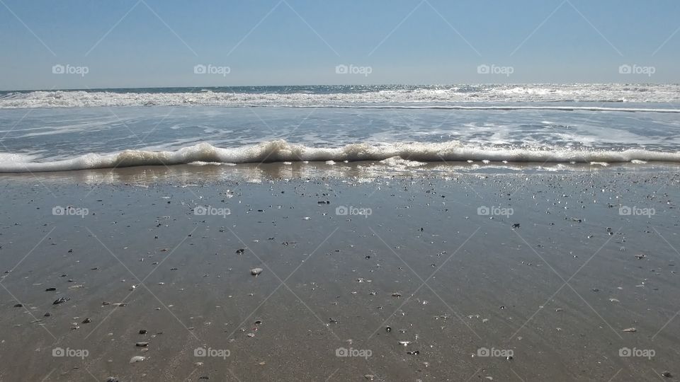 ocean waves on shore against blue sky
