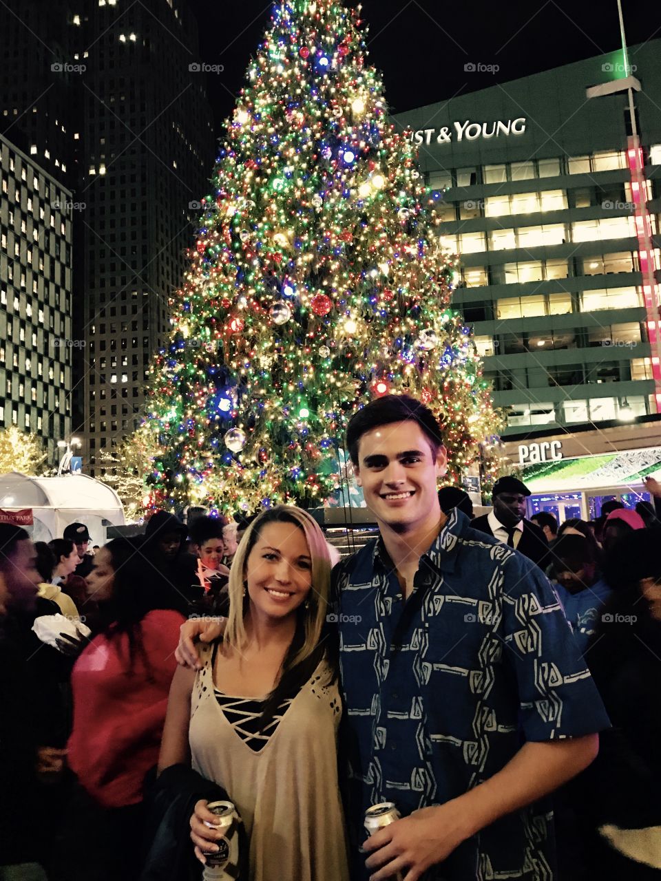 Happy couple standing in front of illuminated christmas tree