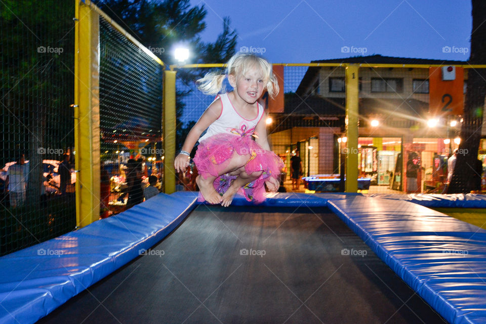 Little gir jumping on a trampoline in a theme park in Alcudia on Majorca.