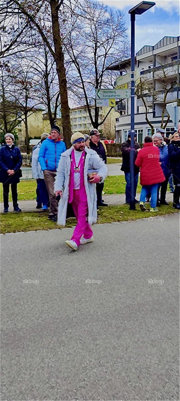 The gentleman in a hot pink suit and a white overcoat is in the carnival parade in “Bad Füssing”, “Bavaria”, Germany on “Mardi Gras” or “Fat Tuesday”, the last day of the festivities. Carnival is called “Fasching” here. 2024. Hypnotic Productions
