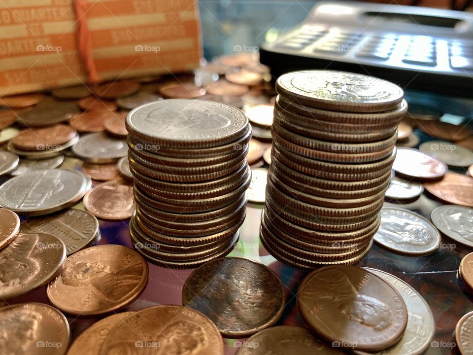 Scattered us coins in the table with segregated quarters. Calculator and coins envelopes.