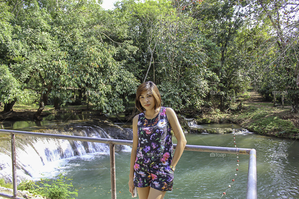 Asean woman and water in the stream is green and bright green tree at Kapo Waterfall Fores Park , Chumphon in Thailand.