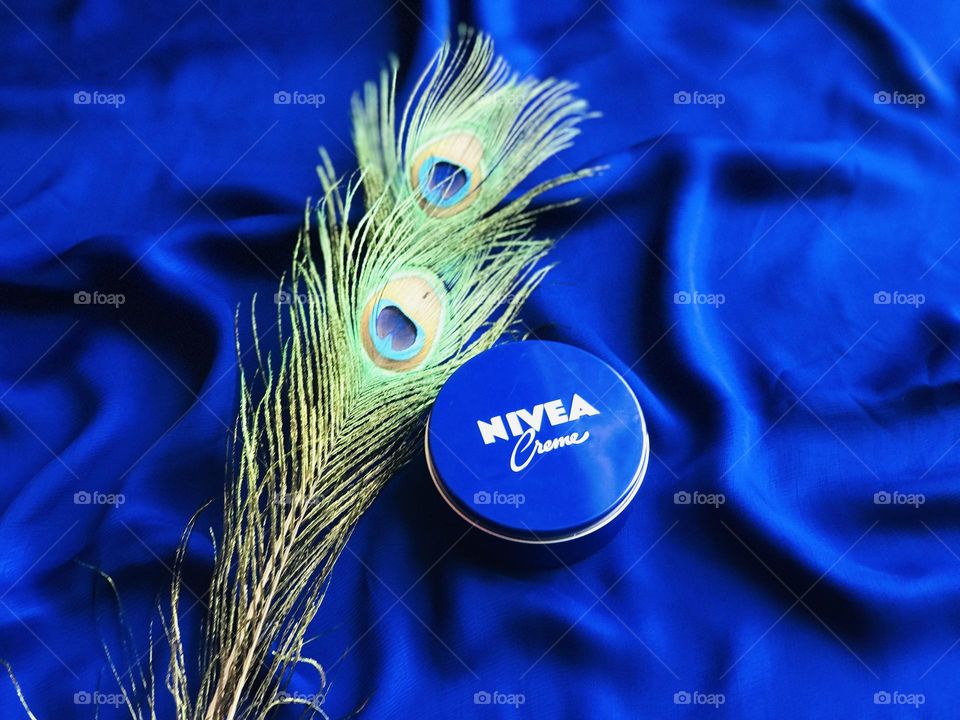 Nivea cream with peacock feathers and blue background.