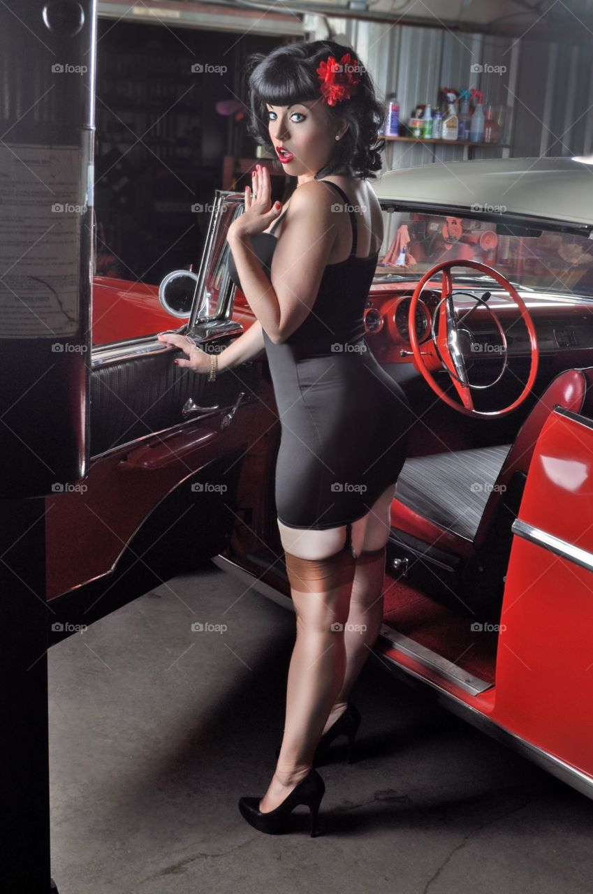 Stylish woman posing near red car
