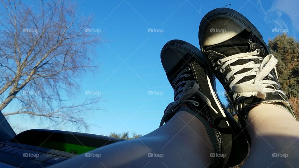 Person seems to be resting while viewing the blue sky in their dirt adorned sneakers that tell there adventures.
