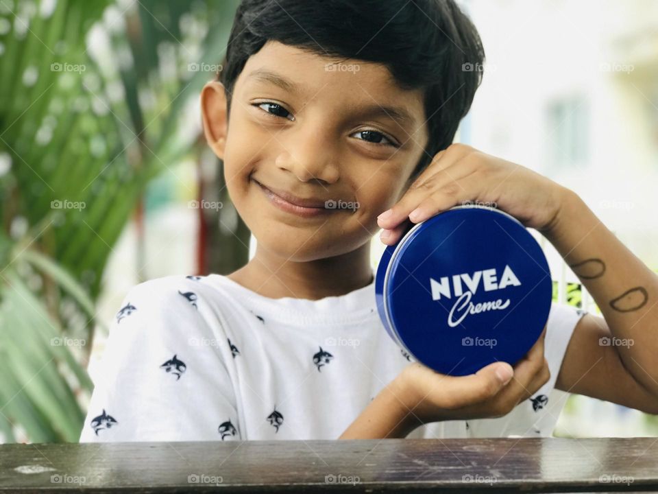 Boy with cute smile and Nivea cream in his hand .