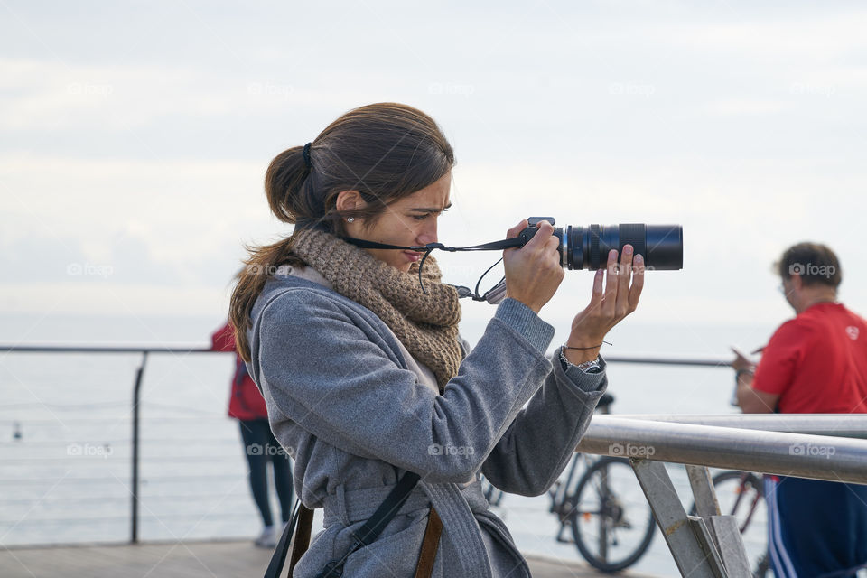Woman standing on pier and photographing