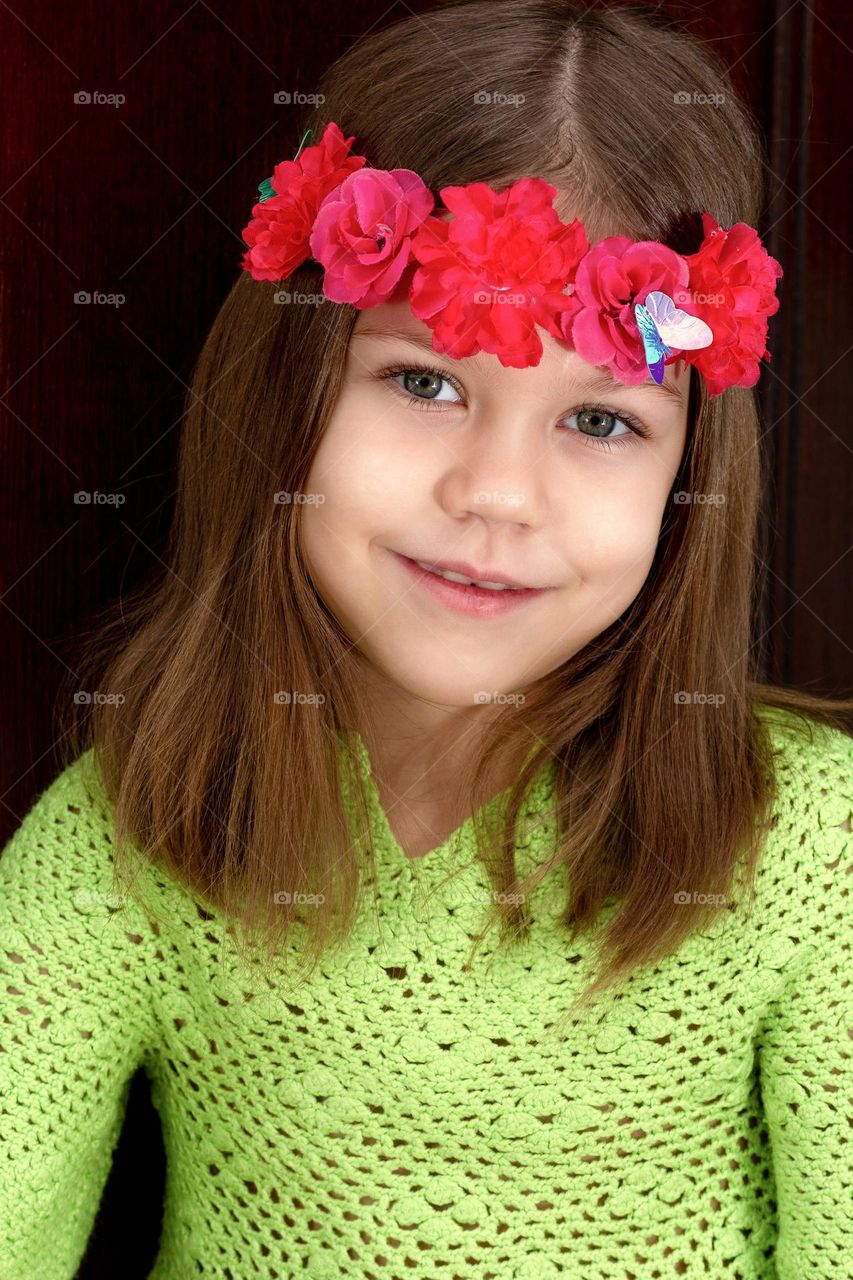 Portrait of beautiful child in green with red garland on head