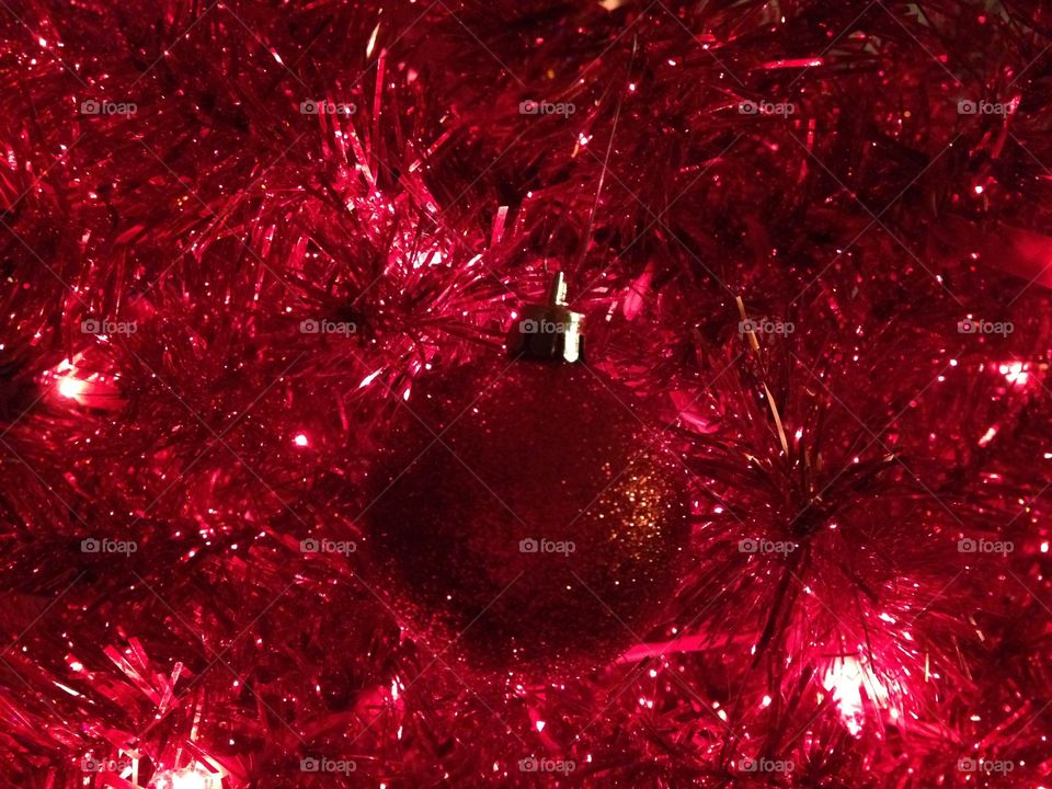 Red glitter Christmas ornament on red tree 