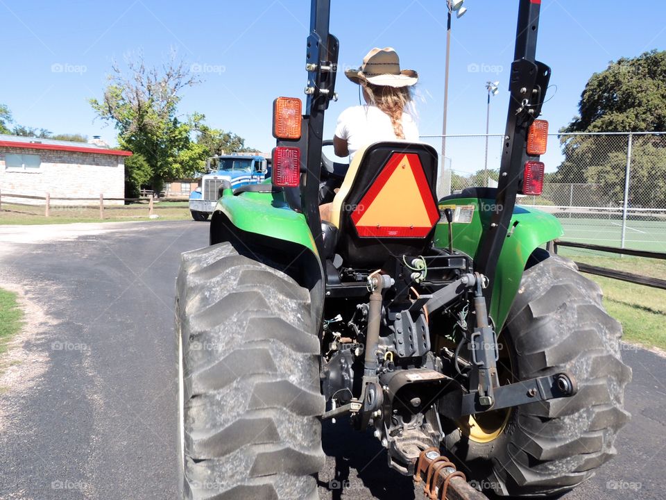 Tractor riding cowgirl in the hill country