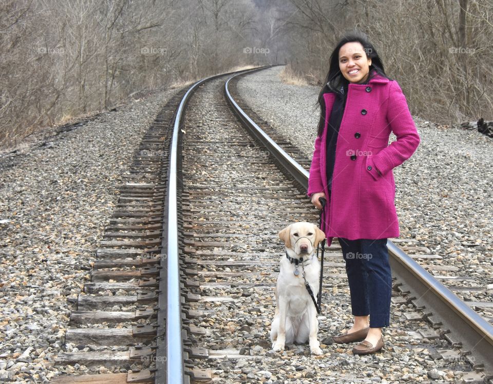 Girl standing on railroad tracks with her dog