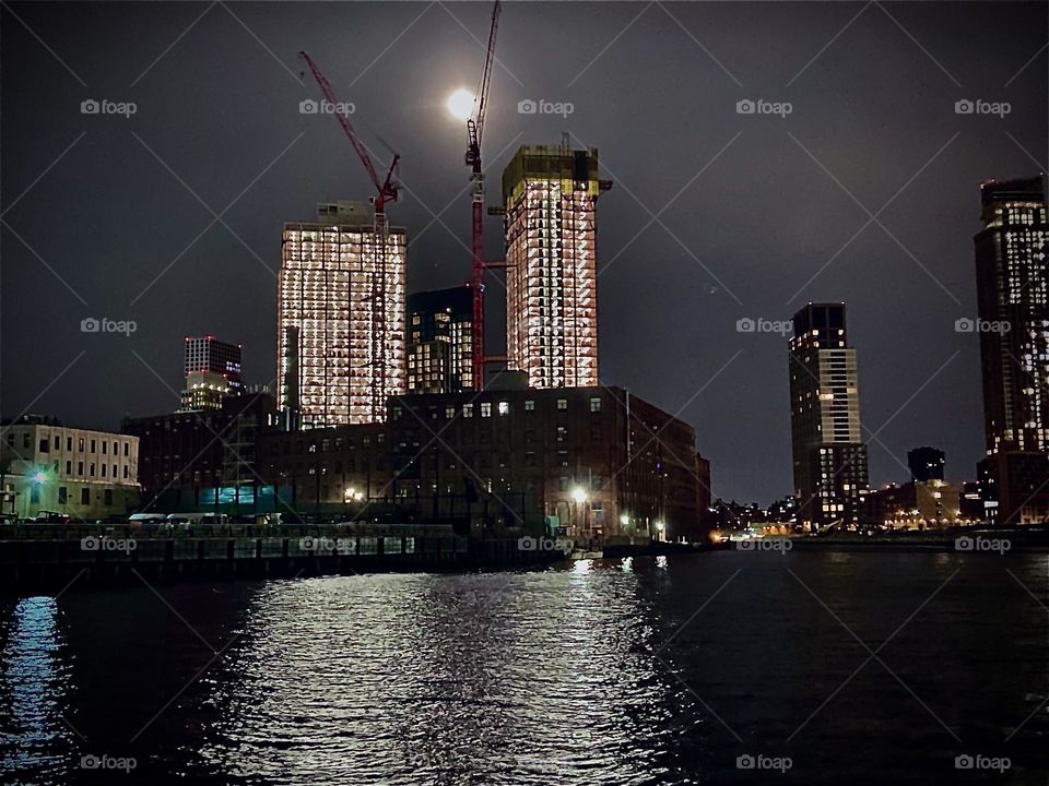 “Newtown Creek” in the “Wee Hours” around 3:30 AM with an exceptionally bright full moon hovering above two high rise buildings that are currently being worked on and are therefore illuminated all night long. 2022. Hypnotic Productions