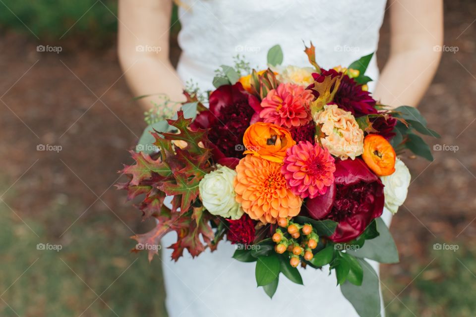 Bride holding her red and orange flowers bouquet 