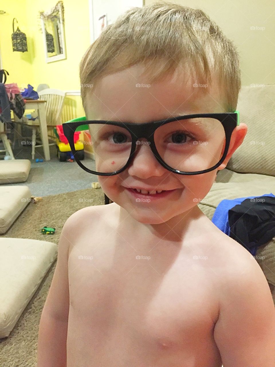 Smiling shirtless little boy wearing big spectacles