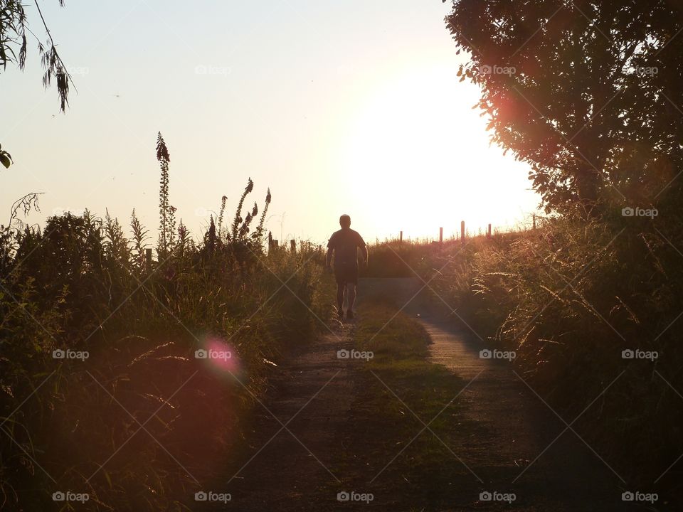 Lonely walk up a country lane back lot by the sun