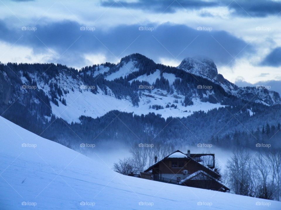 Un chalet dans la neige et les montagnes enneigées