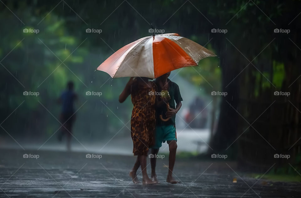 Two Children Carrying An Umbrella In The Rain
