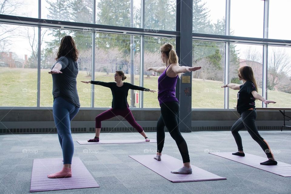 Young woman teaches a yoga session while looking out to a beautiful landscape of mountains 