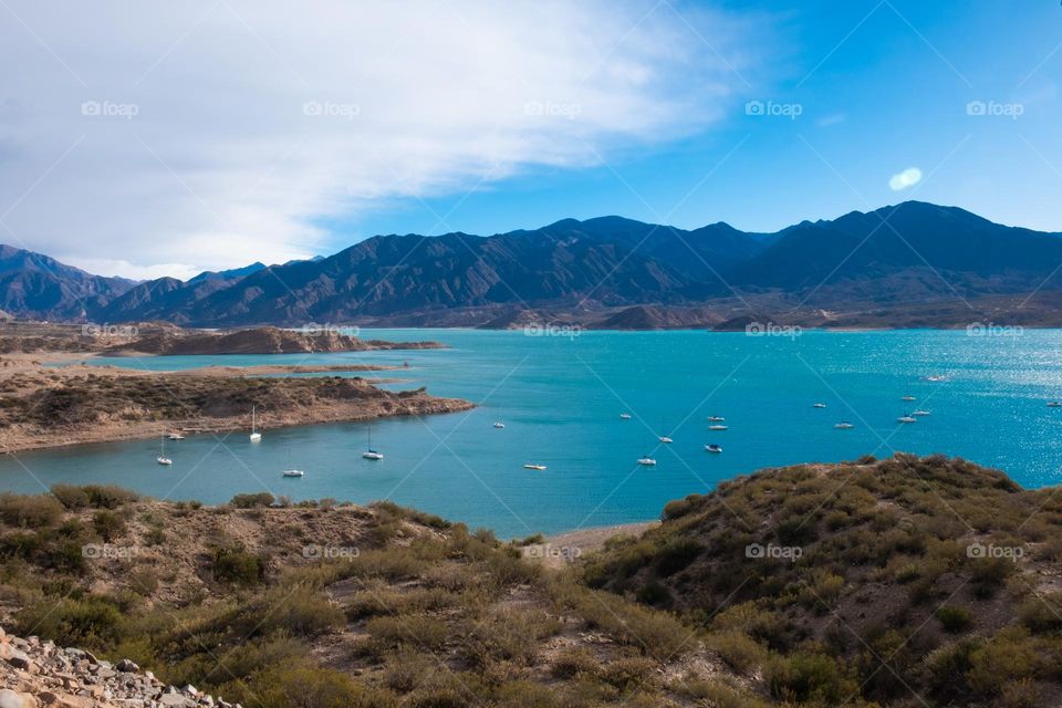 Mountain lake with crystal clear blue water surrounded by red mountains. Andes