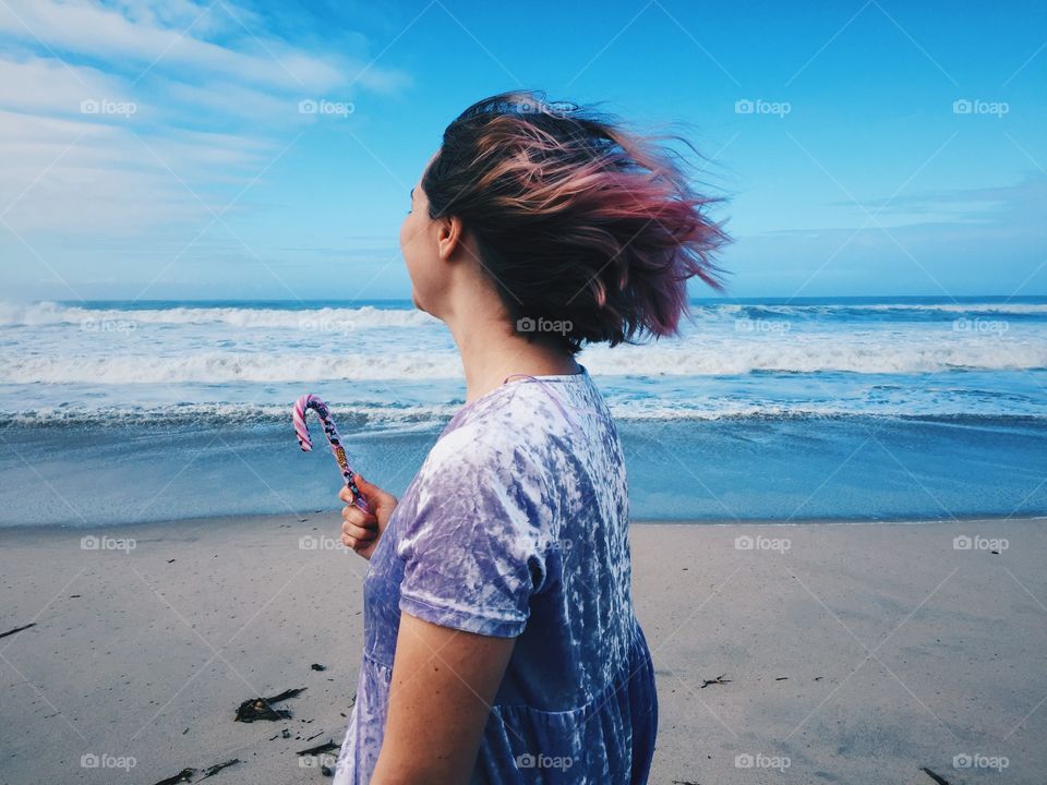 A girl with a Christmas candy watching the ocean 