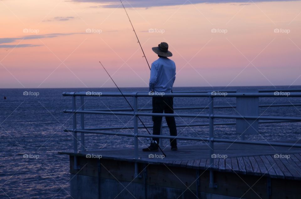 A man wearing a hat takes in a morning catch and fish off a pier of the Absecon bay in Atlantic city, New Jersey.