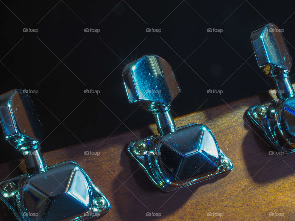 Musical instrument classical acoustic guitar of light color with steel pins and silver strings on a dark background