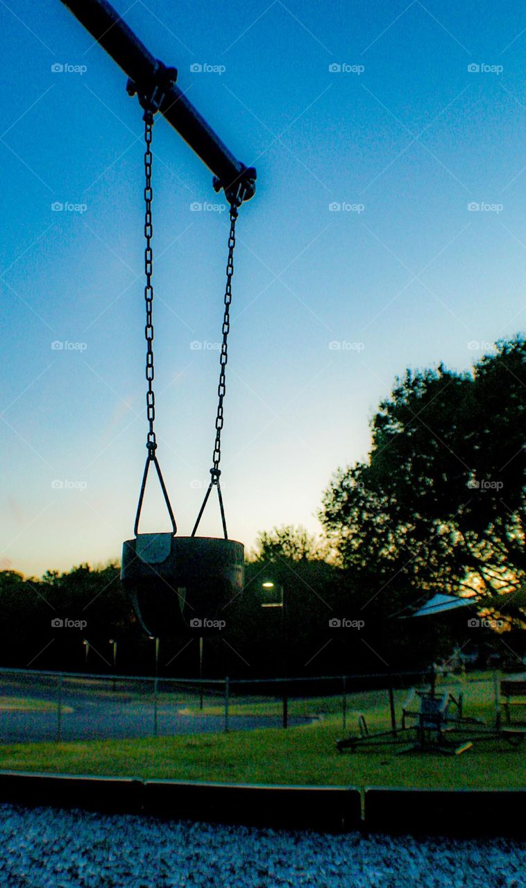 A swing rests idyl at the end of the day, the colors of the sunset making barely visible 