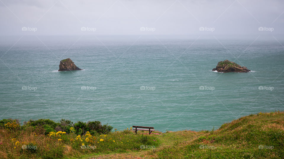 Bench at the edge of cliff with a view at sea rocks.