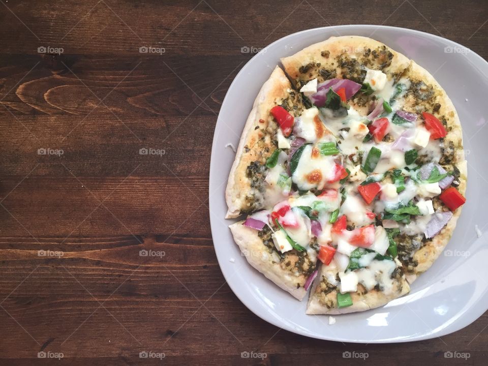 Vegetarian spring pizza with pesto sauce, red onions, red peppers, spinach, green onion and feta cheese on a whole wheat pita. A fun recipe that is tasty!