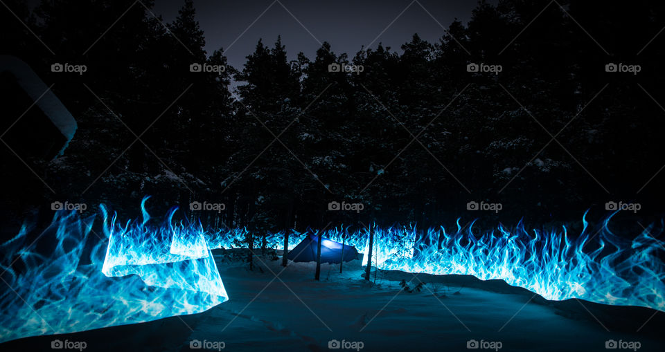 Fake blue fires in the winter forest with tent.