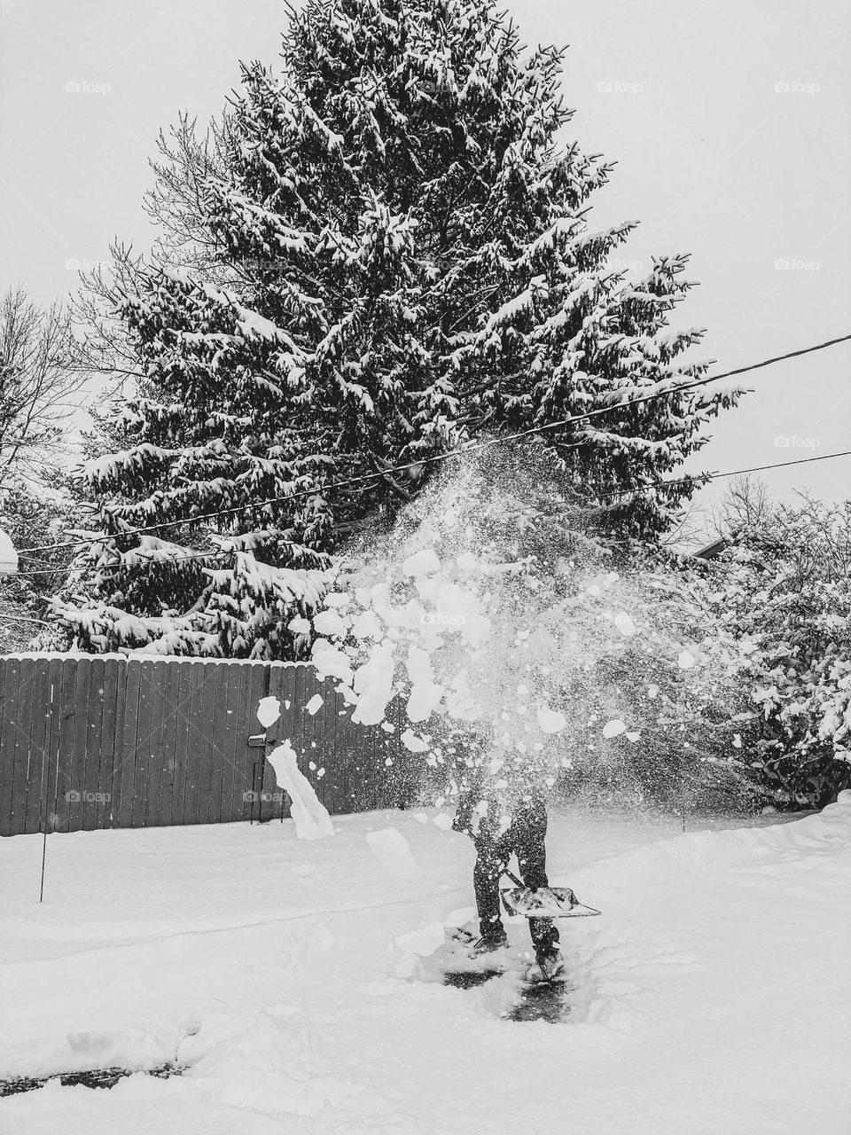 Making art with the snow and ice, throwing snow into the air, snowstorms in the Midwest, man shovels snow into art, making art with nature 