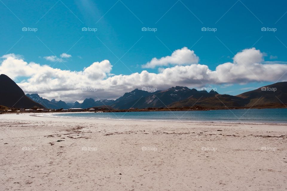 White sand beach in Norway with mountain view behind 