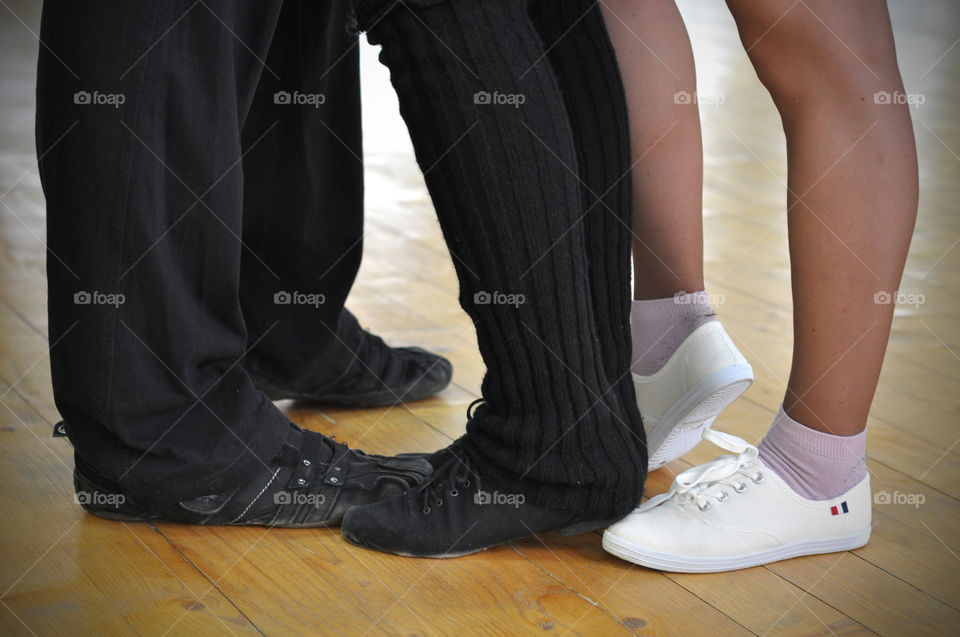 Tree dancing people standing close to each other during the dance and their feet 