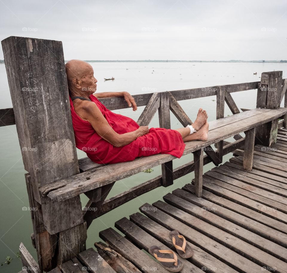 Colorful local life , Monk sit on bench at U bien , the longest wooden bridge in Mandalay Myanmar