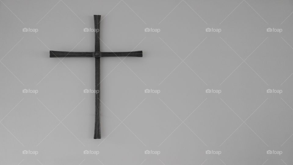 Steel christian cross on a white wall