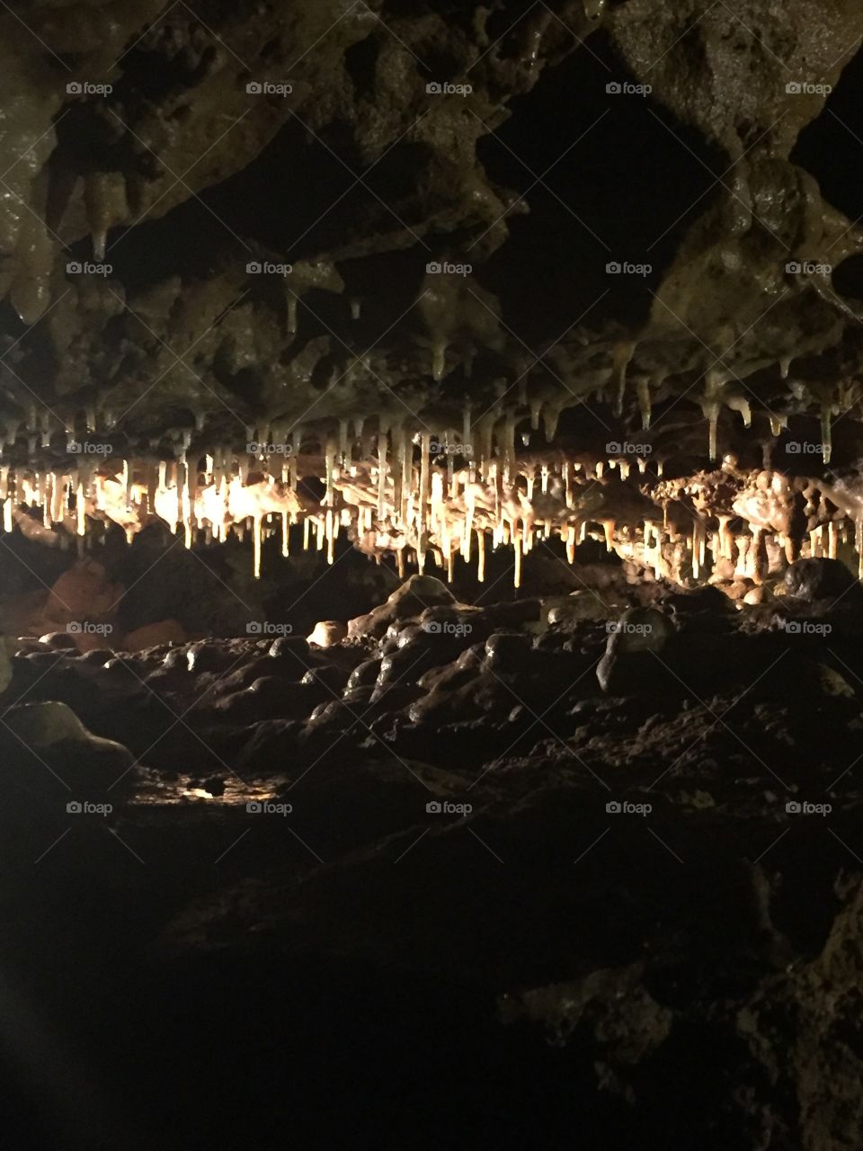 A dark gap in a cave wall full of glistening  stalactites and stalagmites beautifully contrasted with the dark shadows between