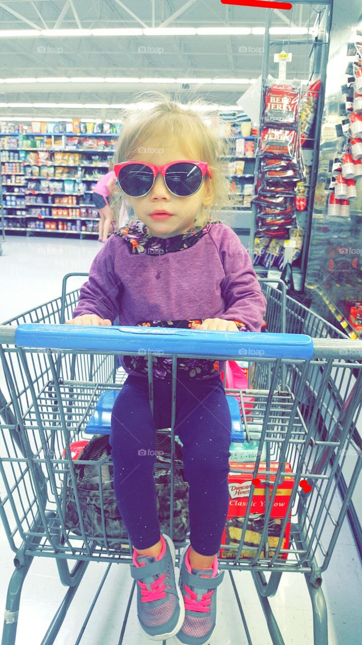 Little Emily in shopping cart with sunglasses on. cute.