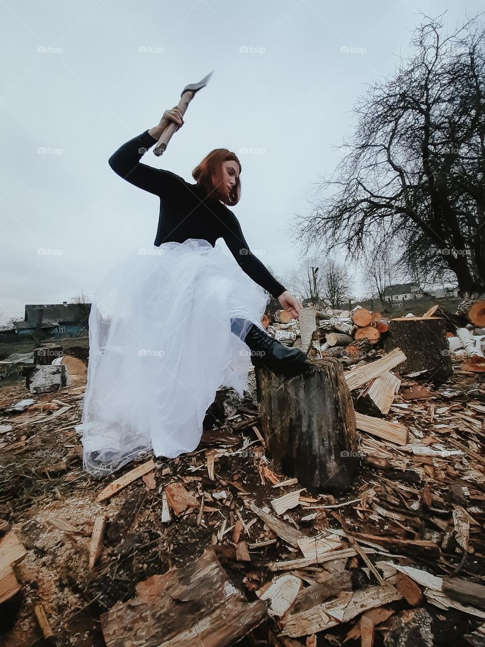 A strong girl chops wood despite her dress