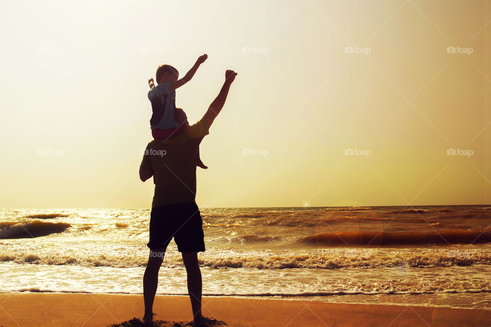 Father and son playing on the beach at the sunset time