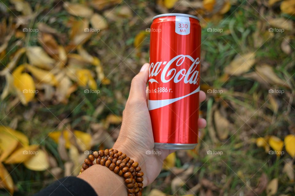 coca cola in hand autumn beautiful background, drinking coca cola outdoor