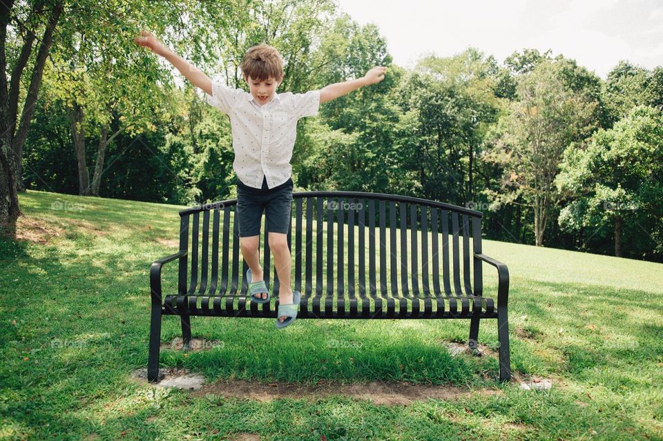 Boy jumping off bench.