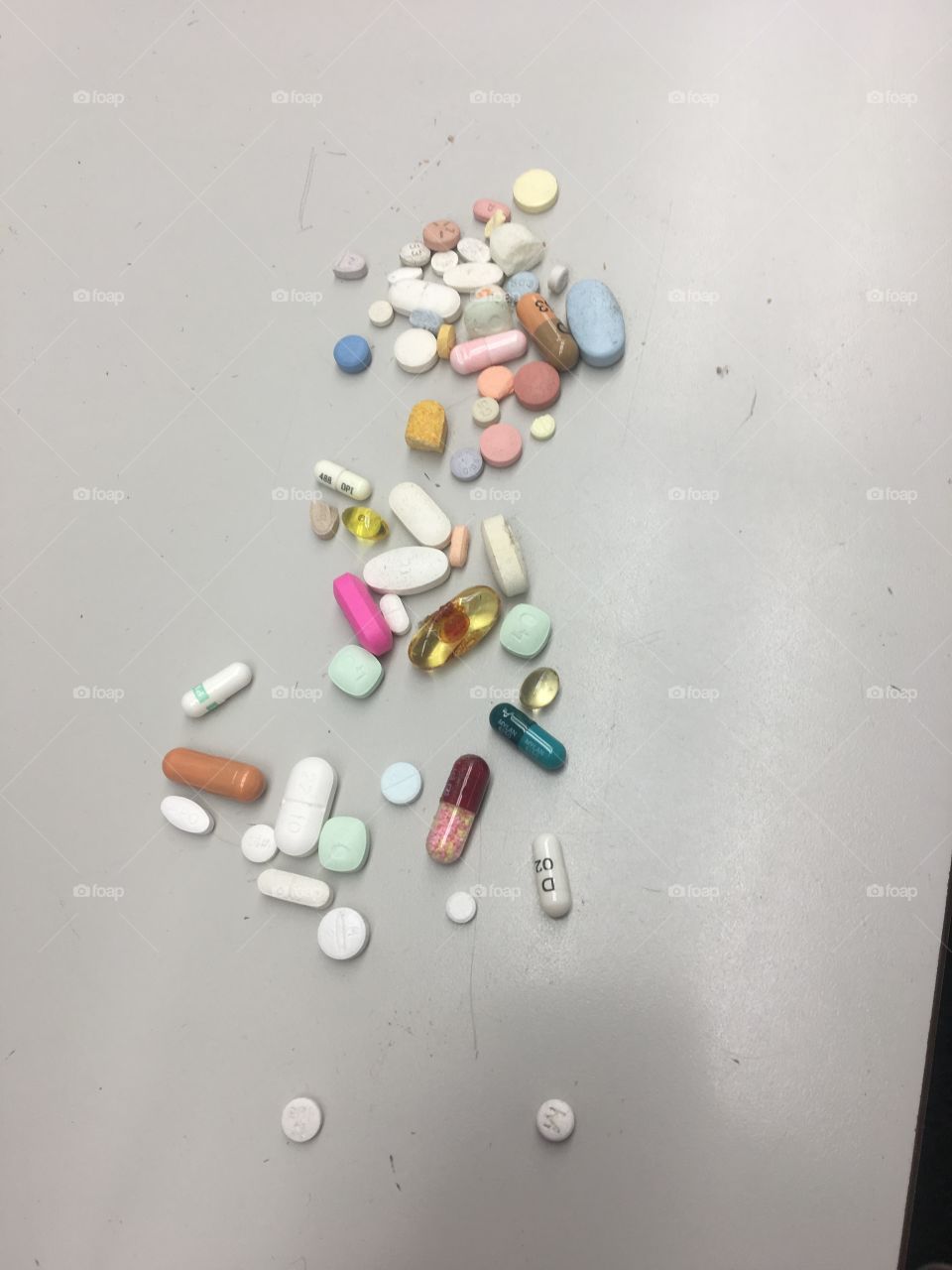 Multiple colors of pills on white floor. 
