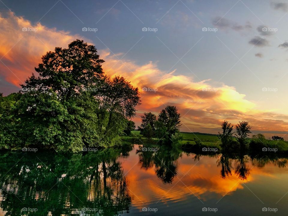 Gorgeous sunrise near pond with accenting cloudscape in the background.