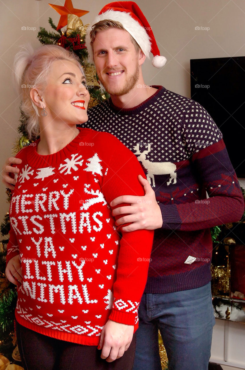 A smiling young couple in Christmas knit ware.
