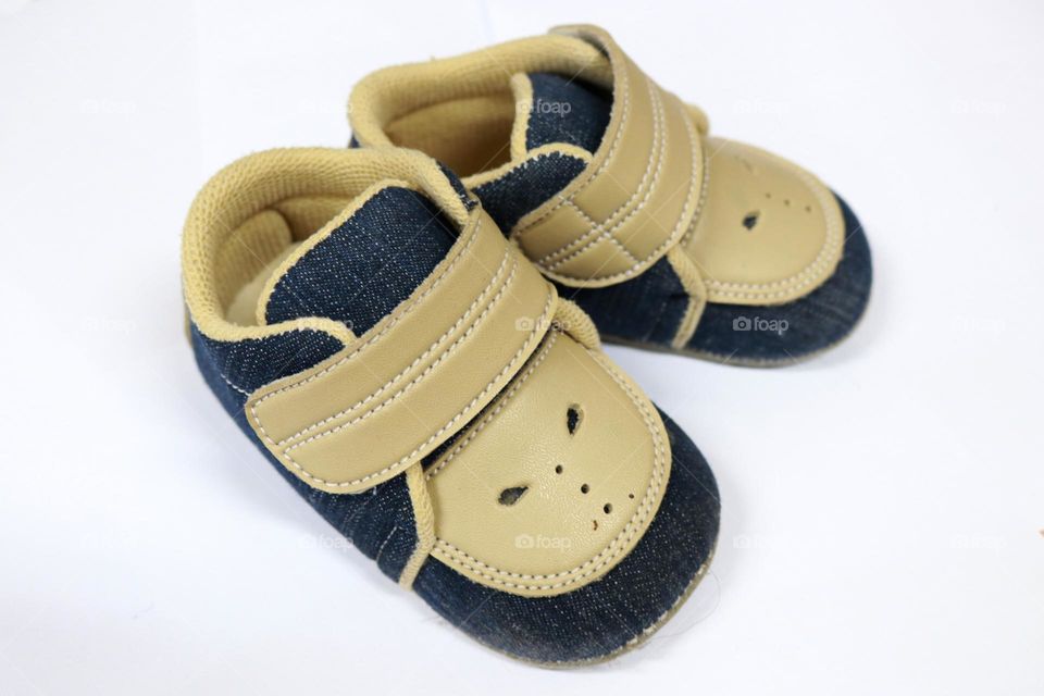 Photo of a pair of children's shoes made of artificial leather. This photo is on a white background