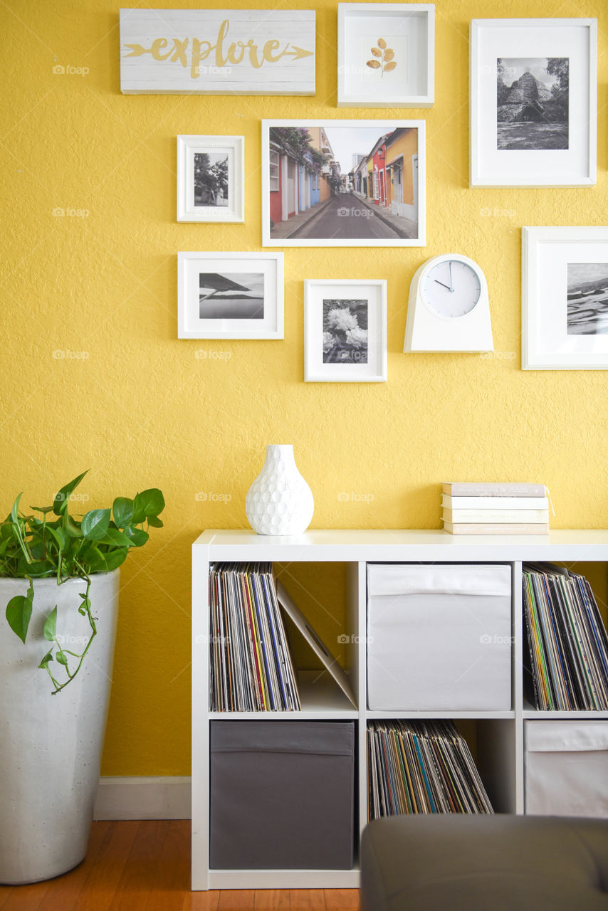 Bookshelf with pictures hanging above it on the wall in a modern home