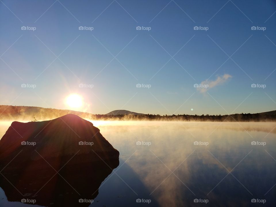 Sun shining through the mist over a lake